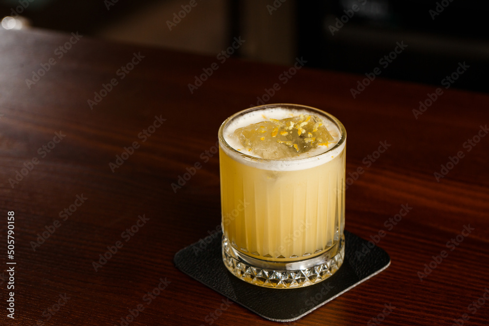 Alcoholic Scotch Whiskey Penicillin Drink Cocktail with Lemon, Honey syrup and Candied Ginger. Cocktail glass on black background