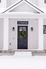 A modern farmhouse front porch, covered in a fresh layer of winter snow.