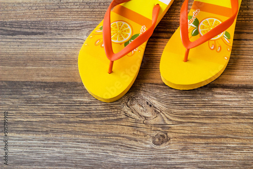 Yellow color flip-flops soft sponge slippers on wooden surface,half view with copy space