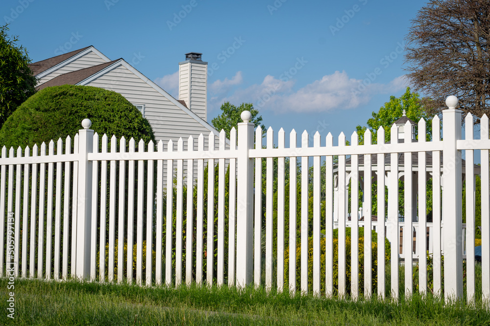 Φωτογραφία White vinyl fence in a cottage village tall thuja bushes behind the fence fencin