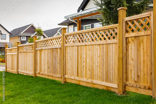 Fotobehang Nice wooden fence around house. Wooden fence with green lawn.