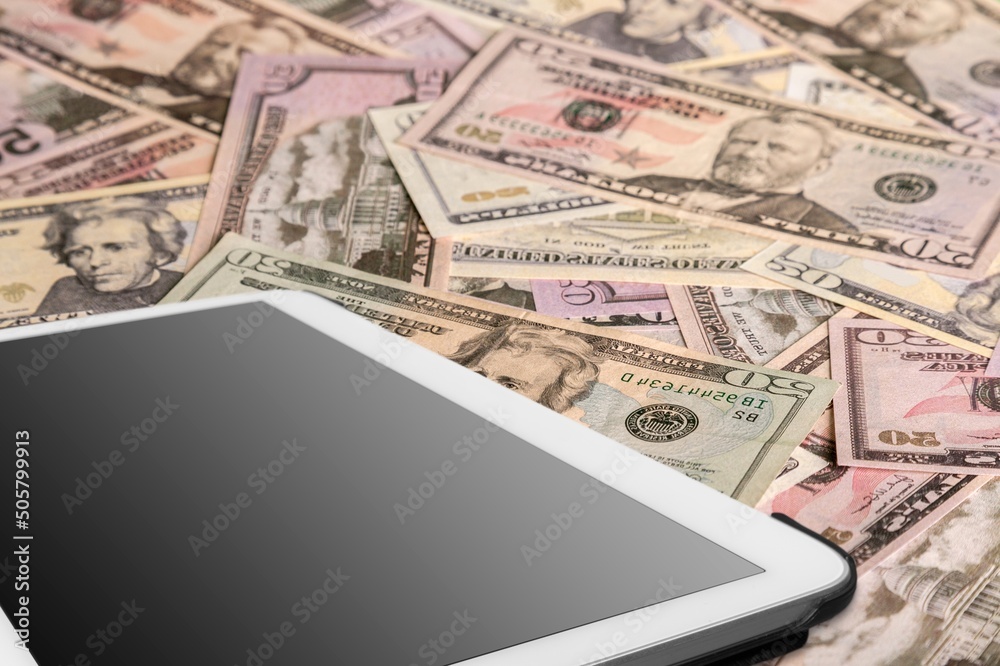 Digital table on stack of dollar currency Digital table on stack of dollar currency