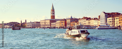 Italy, Venice, panoramic image of Riva degli Schiavoni, the Venice Promenade, with passenger boats. City skyline banner. Church Santa Maria della Salute, Doge's palace and St Mark's Campanile. photo