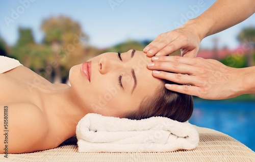 Beauty and relaxation concept - beautiful young woman on massage at spa over tropical beach background. © BillionPhotos.com