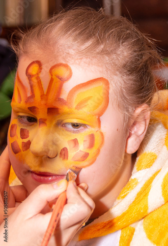 A child in kugurumi. A girl in a giraffe costume with a beautiful, bright, themed aquagrim on her face. photo