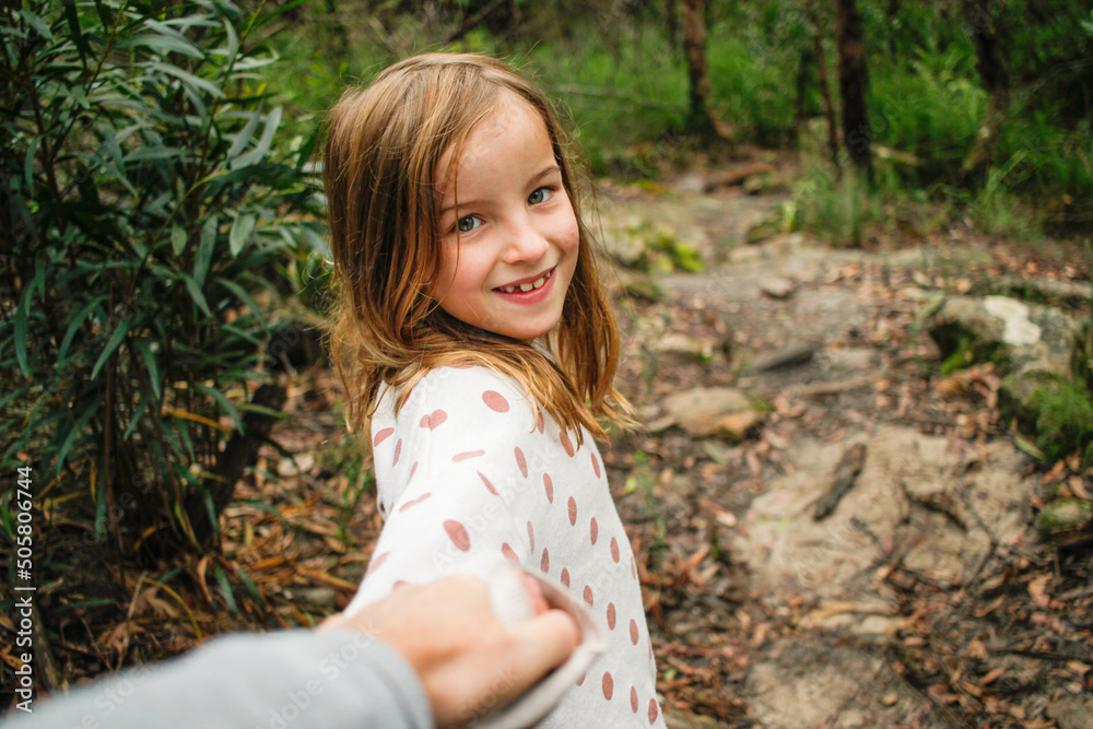 Young girl smiling in the wild holding parents hand on an adventure Young girl smiling in the wild holding parents hand on an adventure