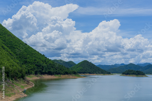 Beautiful lake view with green forests, blue sky and white clouds. © Sumeth