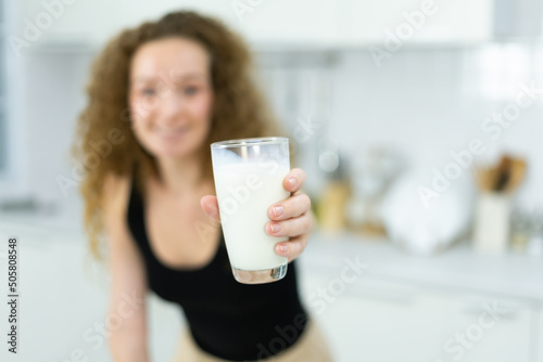 woman happy, smile, show milk, stand, look at camera in kitchen with copy space. beautiful caucasian woman cooking healthy diet fruit or vegetable in kitchen
