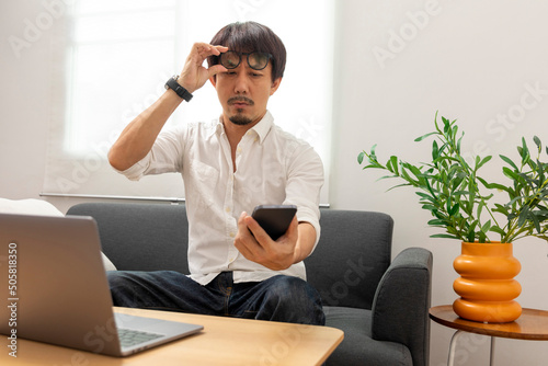 Photography Middle age Asian man squint eye to look at the phone due to long eye sighted problems, which makes vision difficult