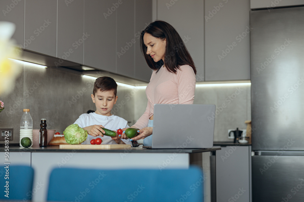 Beautiful mother and small cute son preparing dinner together with vegetables in kitchen. Beautiful mother and small cute son preparing dinner together with vegetables in kitchen.