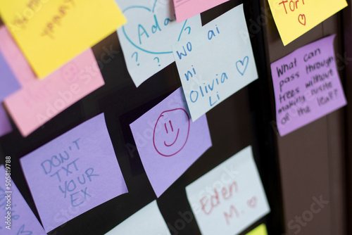 Closeup of a smiley face drawn on a note among other different colored sheets of note papers with various messages on a storefront window at a university campus. photo