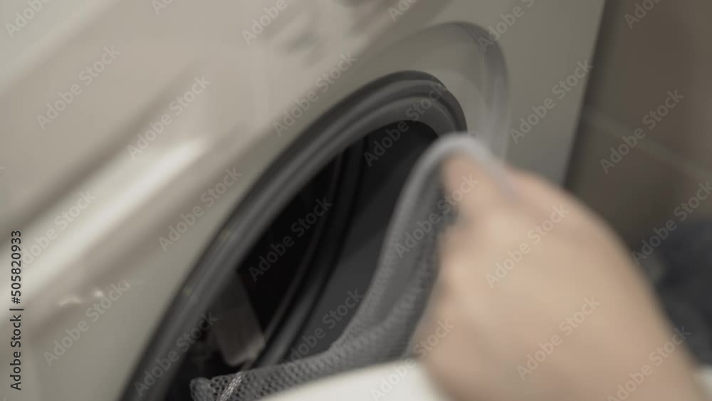 Person prepares dirty laundry for cleaning in a washing machine. Women's hands fold clothes into a mesh bag. Household chores. Hygiene and cleanliness. Person prepares dirty laundry for cleaning in a washing machine. Women's hands fold clothes into a mesh bag. Household chores. Hygiene and cleanliness.