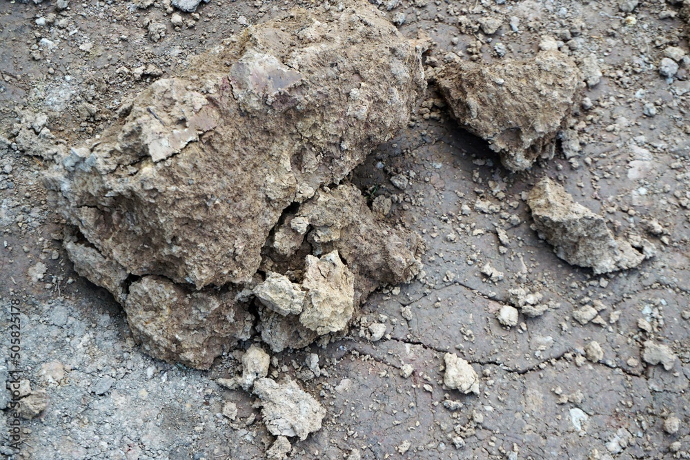 Grau-braune Felsbrocken auf nasser grauer Erdfläche Grau-braune Felsbrocken auf nasser grauer Erdfläche