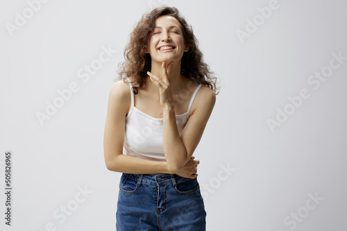 Joyful awesome curly beautiful woman in basic white t-shirt crossing hands smiles at camera posing isolated on over white background. People Emotions Lifestyle concept. Copy space