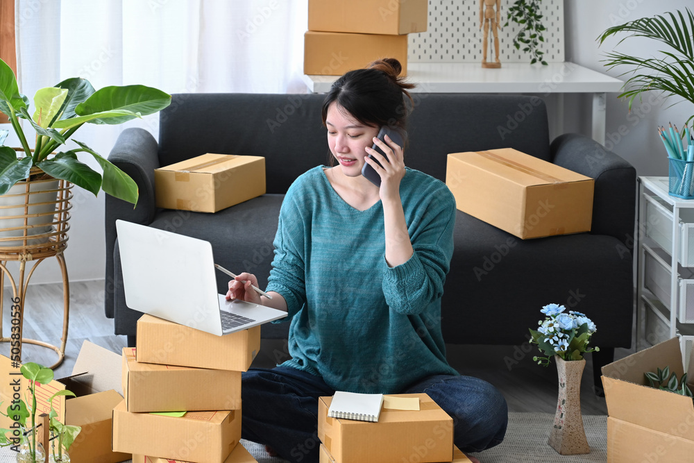 Startup small business entrepreneur receive order on mobile phone and using laptop at home. E-commerce, Online selling concept Startup small business entrepreneur receive order on mobile phone and using laptop at home. E-commerce, Online selling concept
