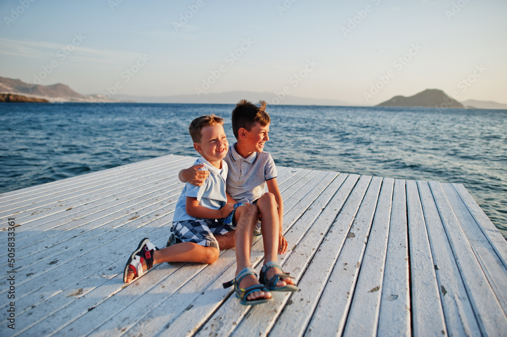 Two brothers sitting at Turkey resort on pier against Mediterranean sea.