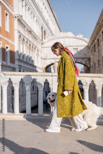 Woman enjoying great view on the Venice canal standing with her dog on the bridge. Concept of happy vacations in Venice. Idea of traveling and walking with dog. Italian style © rh2010