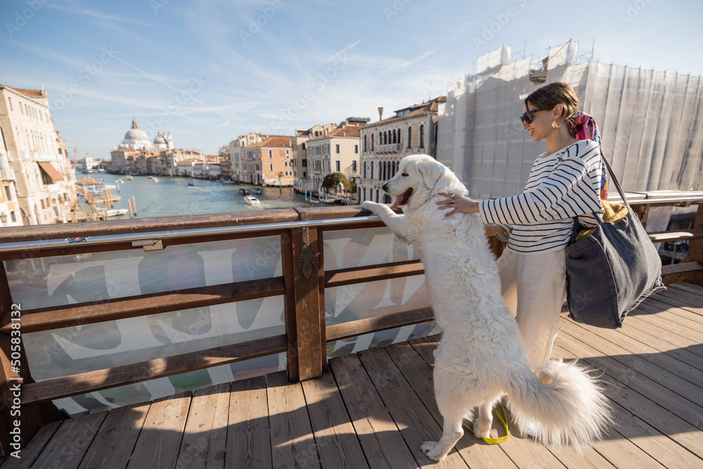Φωτογραφία Woman hugs her dog while standing on the Academy bridge, enjoying great view on famous Grand Canal in Venice
