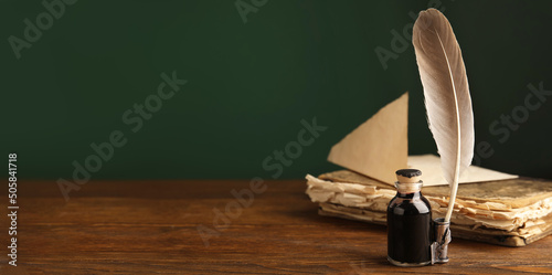 Quill, bottle of ink and old book on wooden table, space for text. Banner design
