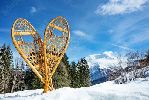 Pair of wooden snowshoes in snow over forest and mountain peaks