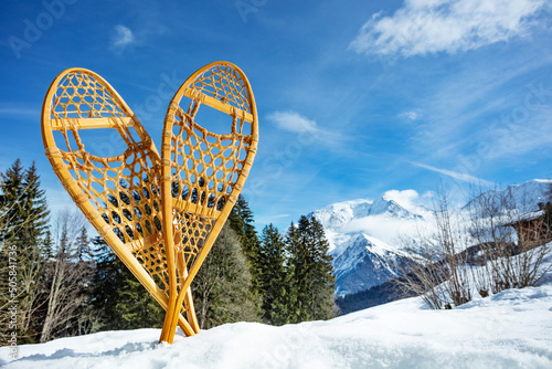 Pair of wooden snowshoes in snow over forest and mountain peaks photo