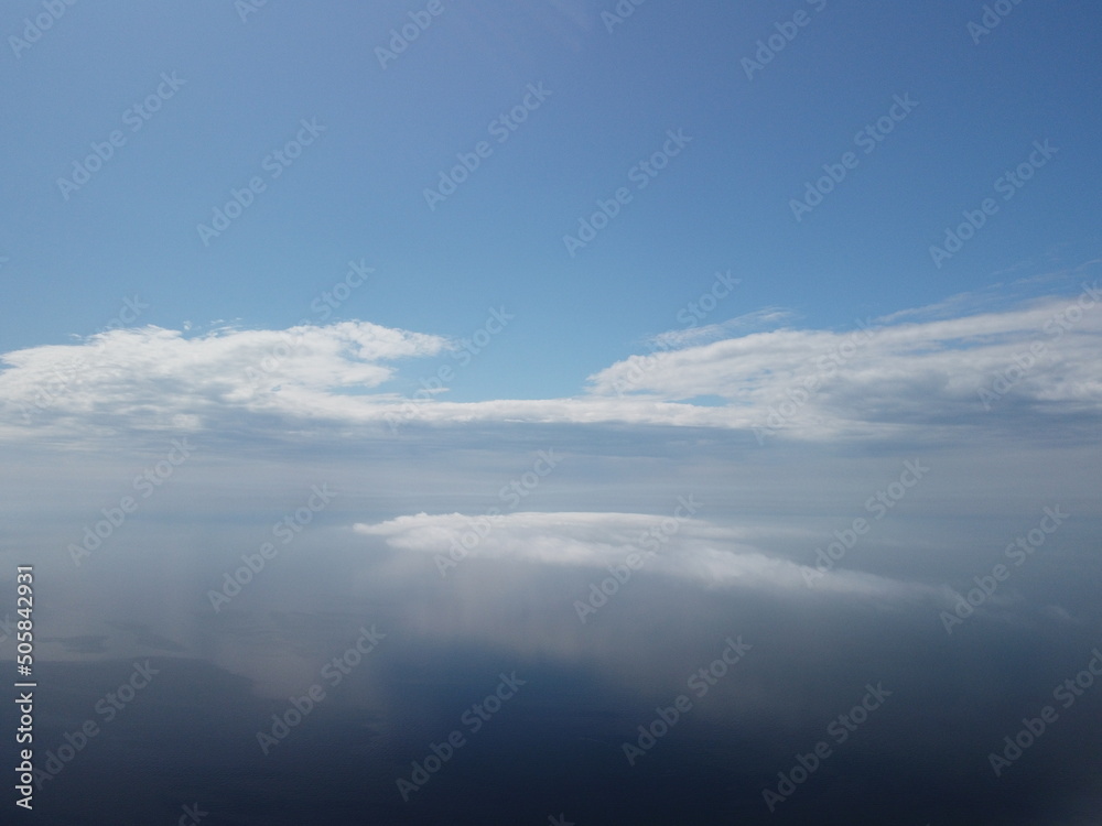 Aerial view. Blue sky sun and fog over calm sea. The drone flies over foggy and fluffy clouds. Abstract aerial nature summer ocean sunset sea and sky background. Vacation, travel and holiday concept.