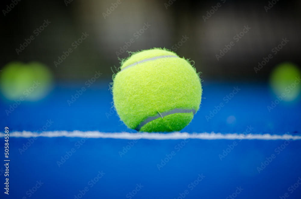 Selective focus, ball in the foreground on a blue paddle tennis court with the background out of focus
