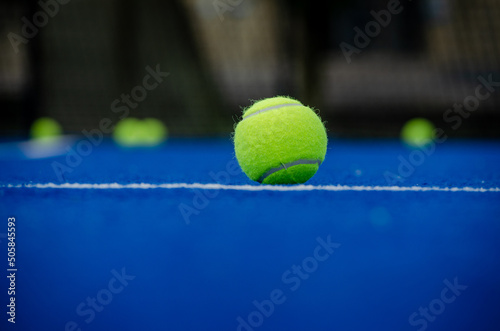 Ball in the foreground on a blue paddle tennis court with the background out of focus. Selective focus.