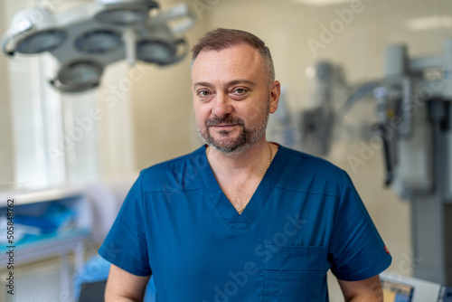 Portrait of handsome professional doctor. Young practitioner in blue uniform.