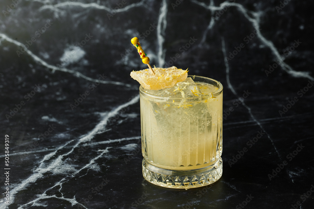 Alcoholic Scotch Whiskey Penicillin Drink Cocktail with Lemon, Honey syrup and Candied Ginger. Cocktail glass on black background