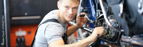 Fotografie, Obraz Male mechanic in a garage repairing a motorcycle