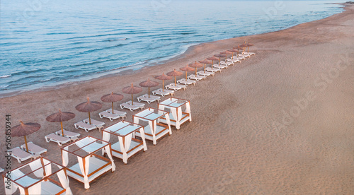 Fotografía horizontal de playa a la hora del atardecer, con sombrillas y camas balinesas. Espacio para texto. photo