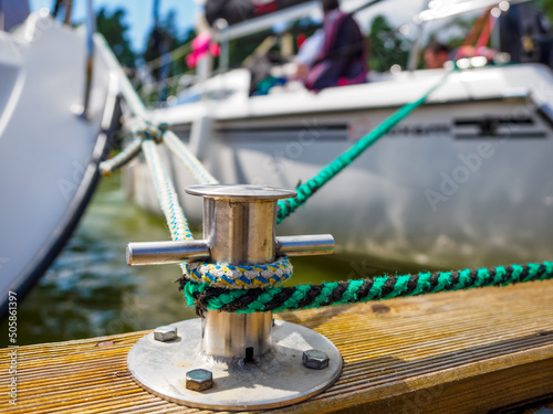 Obraz na plátně A white sailing boat moored with a line tied around a metal fixing