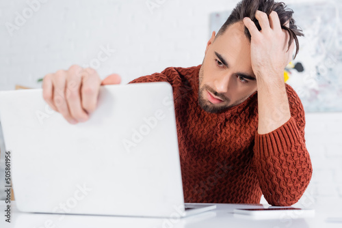 Картината върху платно depressed bookmaker touching head while looking at blurred laptop