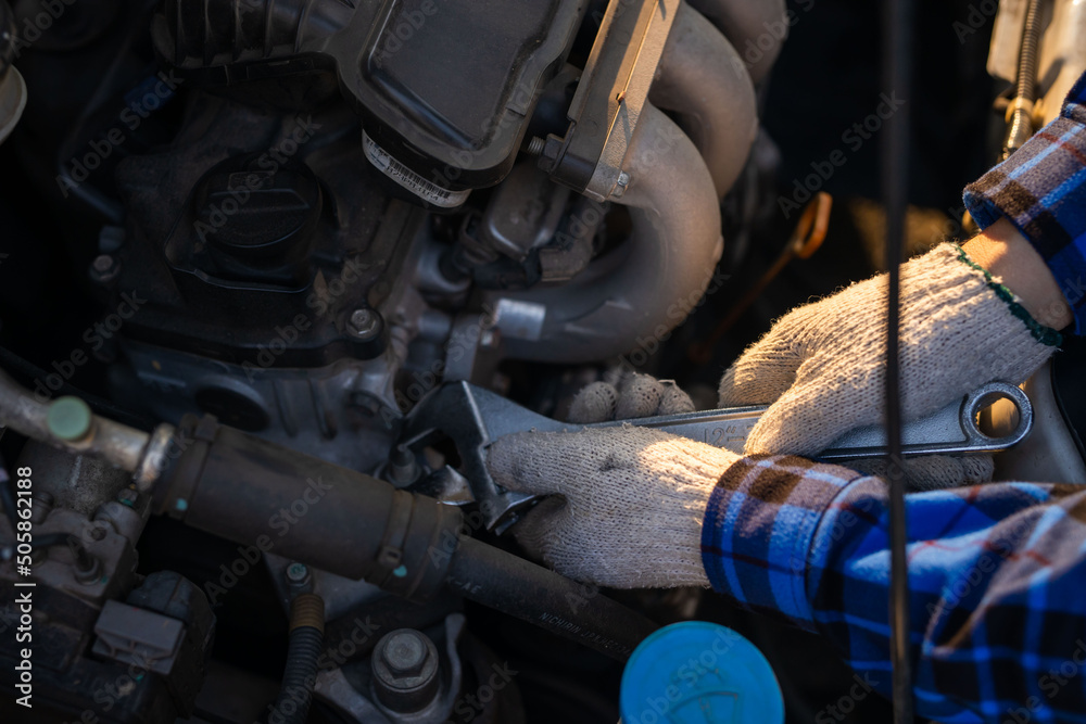 Close-up hands of auto mechanic are using the wrench to repair and maintenance auto engine is problems at car repair shop. Concepts of car care check and fixed and services insurance.