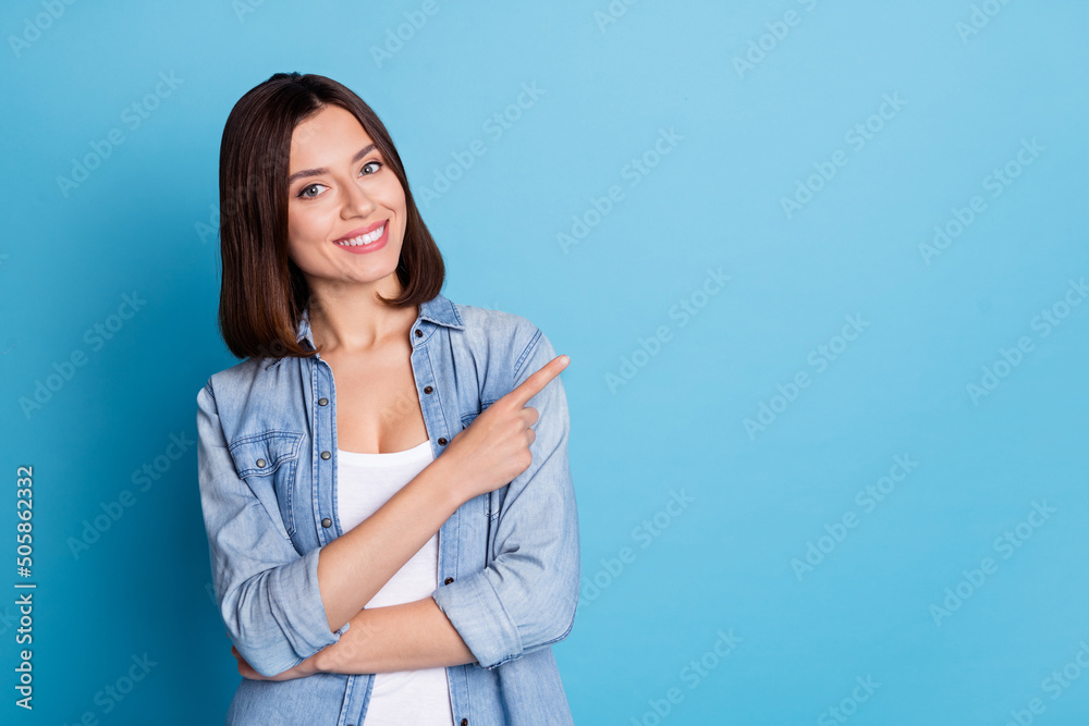 Portrait of positive pretty lady indicate finger empty space promotion isolated on blue color background - obrazy, fototapety, plakaty 