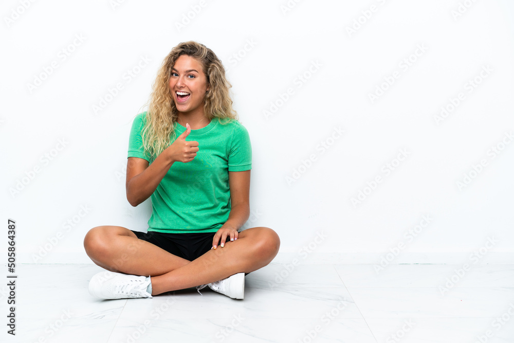 Girl with curly hair sitting on the floor giving a thumbs up gesture Girl with curly hair sitting on the floor giving a thumbs up gesture