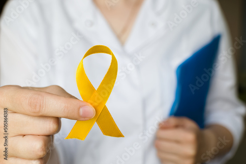 International Childhood Cancer Day. Female doctor in white coat holds yellow ribbon. Sarcoma Awareness, bladder cancer. Leukemia cancer awareness. World Multiple Sclerosis day. I Am and I Will. photo