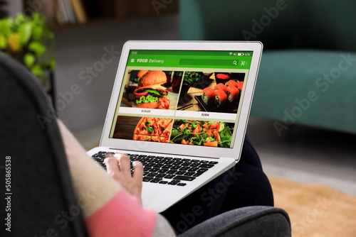 Man using laptop for ordering food online at home, closeup. Concept of delivery service