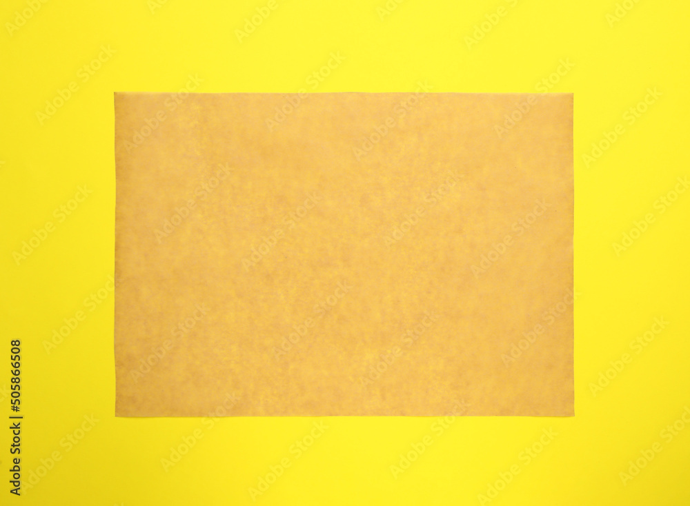 Sheet of brown baking paper on yellow background, top view Sheet of brown baking paper on yellow background, top view