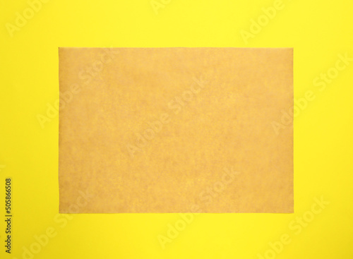 Sheet of brown baking paper on yellow background, top view © New Africa