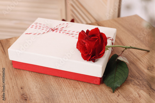 Gift box and beautiful red rose on wooden table indoors. Happy Valentine's Day