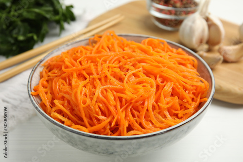 Delicious Korean carrot salad in bowl on white wooden table