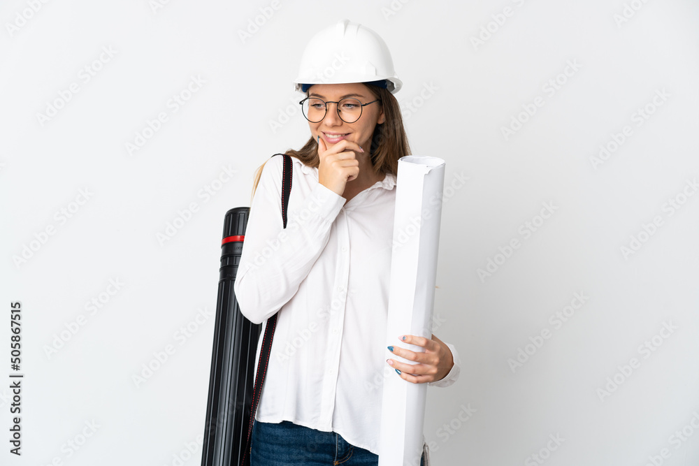 Young Lithuanian architect woman with helmet and holding blueprints isolated on white background looking to the side and smiling Young Lithuanian architect woman with helmet and holding blueprints isolated on white background looking to the side and smiling