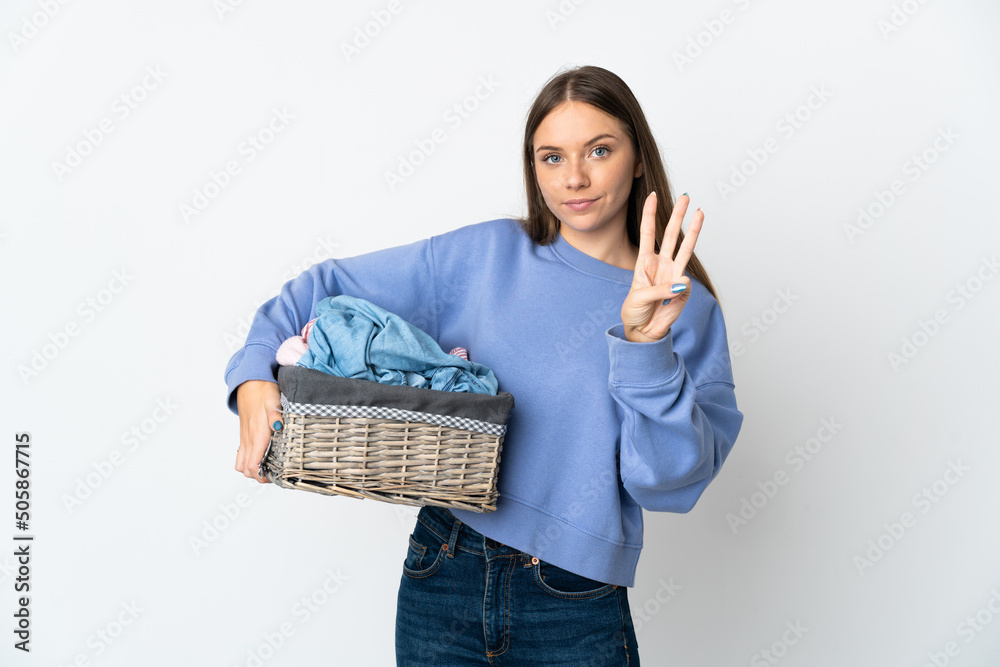 Young Lithuanian woman holding a clothes basket isolated on white background happy and counting three with fingers Young Lithuanian woman holding a clothes basket isolated on white background happy and counting three with fingers