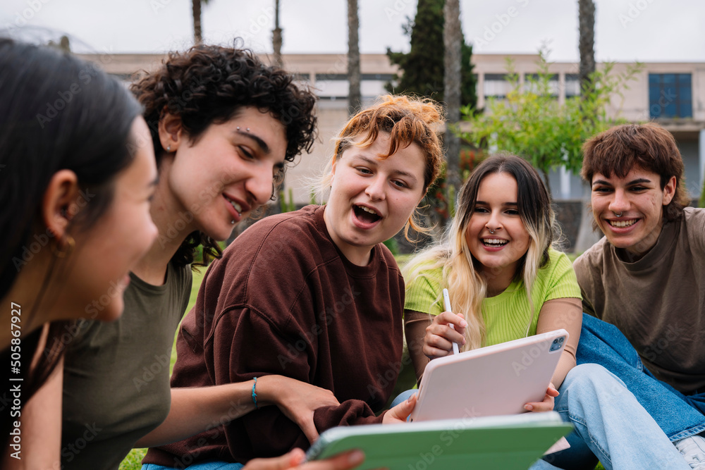 Group of college students using tablets on campus grass Group of college students using tablets on campus grass