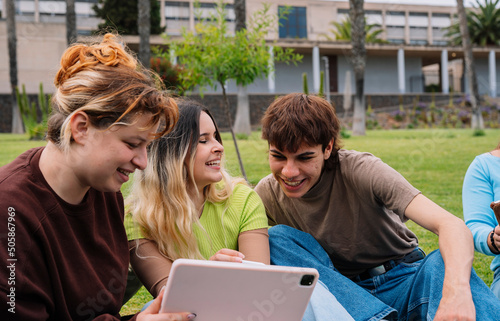 Group of college students using tablets on campus grass