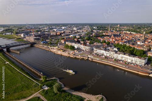 Medieval city seen from above with inland coast guard patrol vessel leaving ripple waves on river IJssel passing IJsselkade boulevard cityscape of tower town Zutphen photo