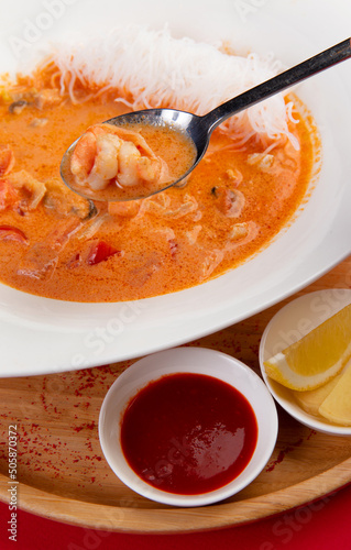 In a spoon Traditional tom yum soup. On a red background. photo