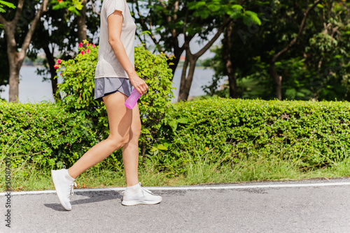 Woman walking in the park with bottle water in her hand health care concept. photo